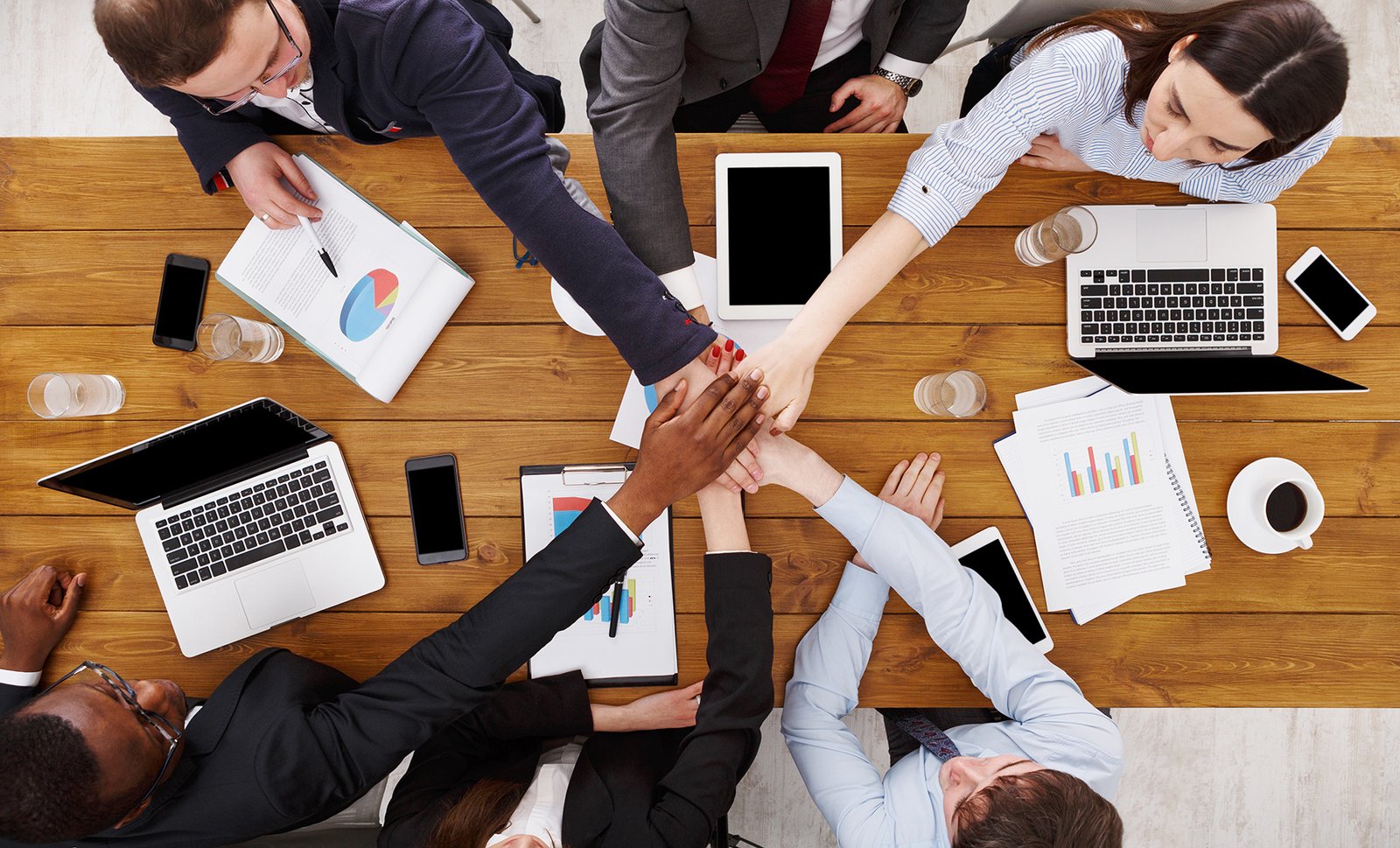 Multiethnic Team put hands together, connection, teambuilding and alliance concept. People in the office, young businessmen and women unite hands for teamwork and cooperation. Top view, overhead; Shutterstock ID 629127548